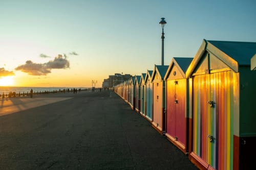 Colorful beach huts at sunset near Horsham with golden hour lighting and seaside promenade