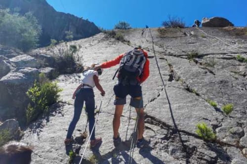 Dois caminhantes escalando rochas em terreno montanhoso perto de Casa da Luz Gerês em Vieira do Minho, Portugal sob céu azul limpo