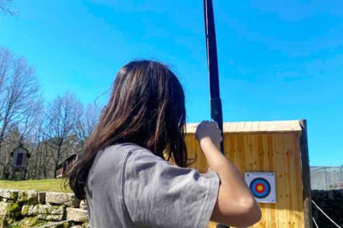 Mulher praticando tiro com arco na Casa da Luz Gerês em Vieira do Minho, Portugal