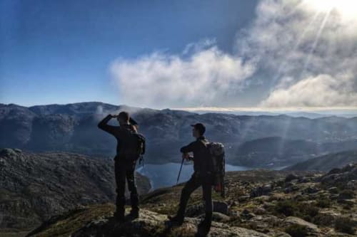 Caminhantes com mochilas observam um lago de montanha e vale perto da Casa da Luz Gerês em Vieira do Minho, Portugal