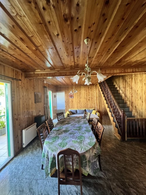 Salle à manger en bois d'Au pied des Sources à Cilaos avec table commune, luminaires suspendus et espace détente
