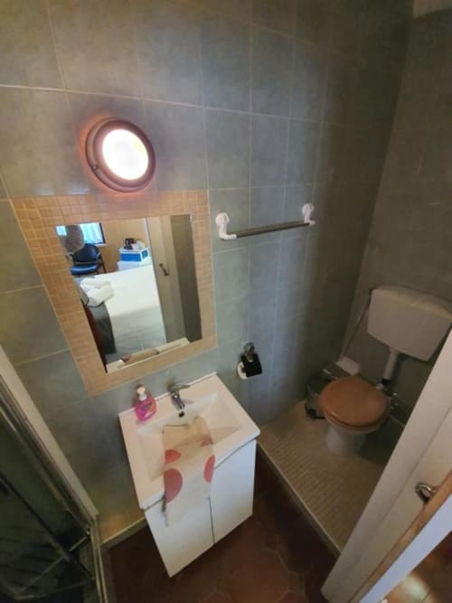 Baño compacto en habitación doble económica del hostel Ocean View Lagos con lavamanos, inodoro, ducha caliente con luz y espejo
