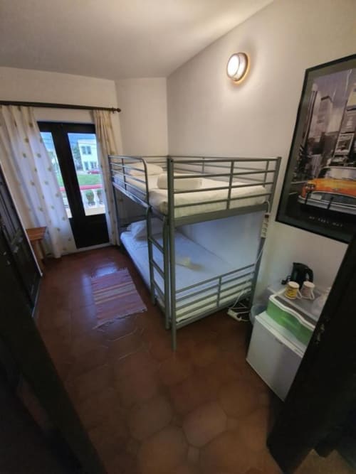Economy bunk bed room at Ocean View Lagos hostel in Lagos, PT, with metal bunk beds, dark wood floor, balcony access, and