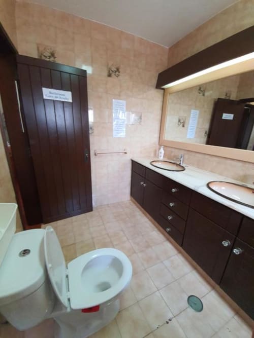 Shared bathroom at Ocean View Lagos hostel in Lagos with dual sinks, toilet, and dark wood vanity
