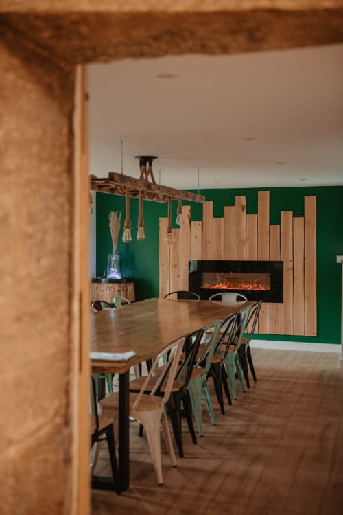 Salle à manger moderne au Repaire Des Darous avec table en bois, chaises, mur vert et cheminée