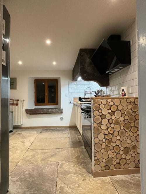 Cuisine moderne du gîte Repaire Des Darous avec panneau accent bois circulaire, carrelage métro blanc et sol en pierre