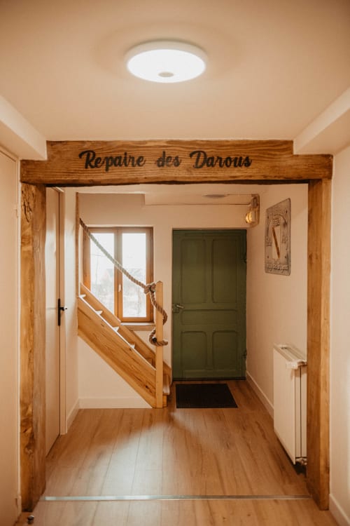 Hall d'entrée rustique en bois du Repaire Des Darous avec escalier et porte verte