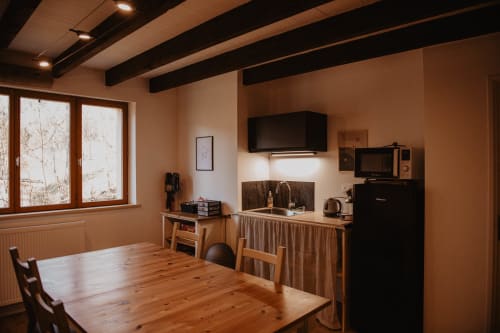 Cuisine et salle à manger chaleureuses au Repaire Des Darous, Saulxures sur Moselotte, avec poutres en bois et électroménagers modernes