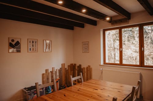 Salle à manger rustique du Repaire Des Darous avec table en bois, plafond à poutres et vue sur la forêt par grandes fenêtres