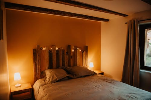 Chambre chaleureuse au gîte Repaire Des Darous à Saulxures sur Moselette, avec tête de lit en bois et éclairage ambiant