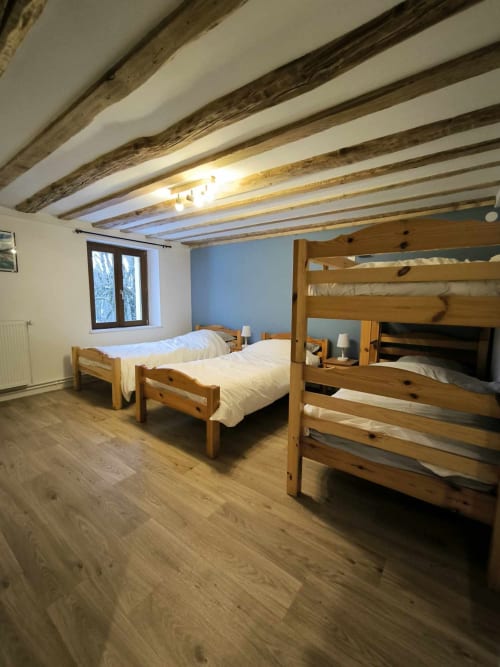 Chambre spacieuse au Repaire Des Darous avec lits superposés en bois, poutres apparentes et parquet à Saulxures sur Moselotte
