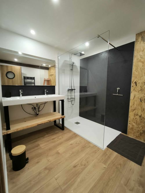 Salle de bain moderne du Repaire des Darous avec double vasque, douche à l'italienne, meuble-lavabo et sol en bois