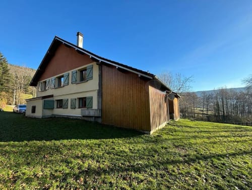 Extérieur du gîte Repaire Des Darous à Saulxures sur Moselotte avec extension en bois, pelouse verdoyante et vue montagne