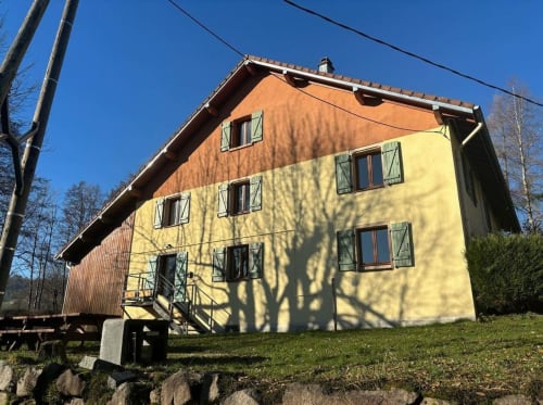 Le gîte Repaire Des Darous à Saulxures sur Moselotte avec façade jaune et orange sous un ciel dégagé
