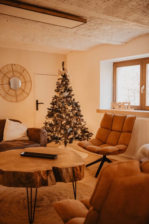 Salon cosy cottageCore au Repaire Des Darous avec sapin de Noël illuminé, sièges en cuir et accents en bois