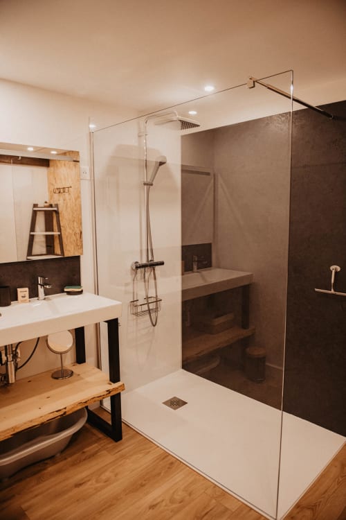 Salle de bain moderne du gîte Repaire Des Darous avec douche à l'italienne, vasque en bois et accents de carrelage foncé