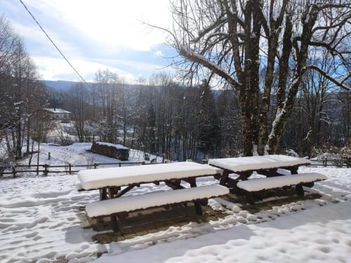 Tables de pique-nique enneigées et arbres nus au gîte Repaire Des Darous, Saulxures sur Moselotte