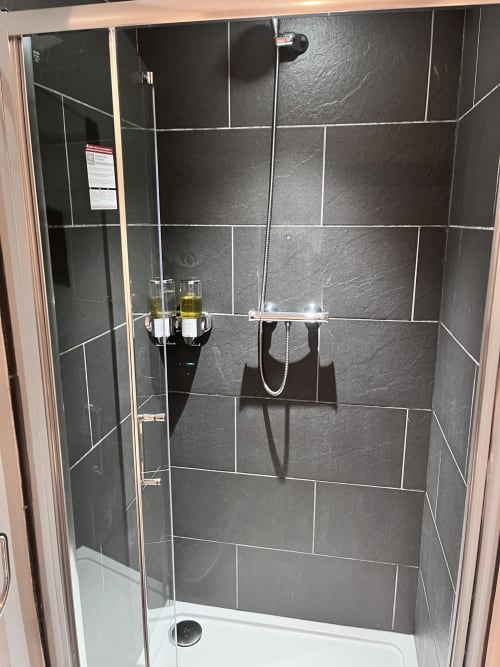 Modern shower enclosure with dark tile walls and white base in Railway Hotel Haydon Bridge deluxe room