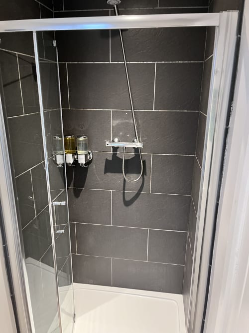 Modern shower enclosure with dark slate tiles and chrome fixtures at The Railway Hotel Haydon Bridge