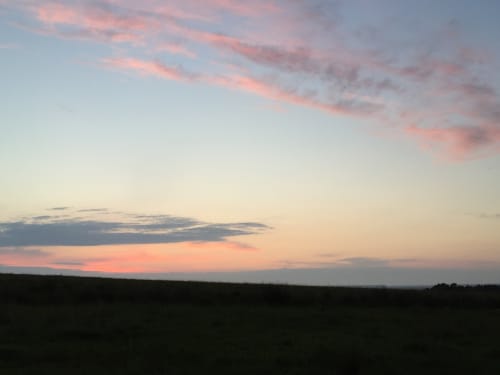 Sunset over fields near The Railway Hotel in Haydon Bridge, Hexham, with pink clouds and silhouetted landscape