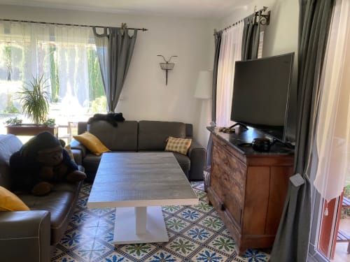 Spacious cottage living room with gray sofa, flat-screen TV, wooden dresser, and garden views at Domaine des Lavarines