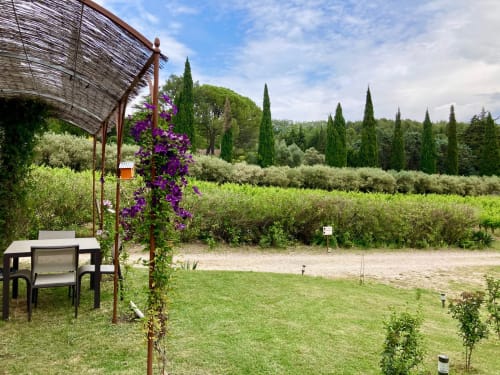 Tuscan garden with purple flowering pergola, olive groves, cypress trees, and seating area at Domaine des Lavarines
