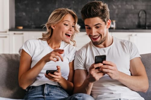 Pareja disfrutando juntos de videojuegos móviles en el sofá del hotel Esto si es vida en Ribadesella