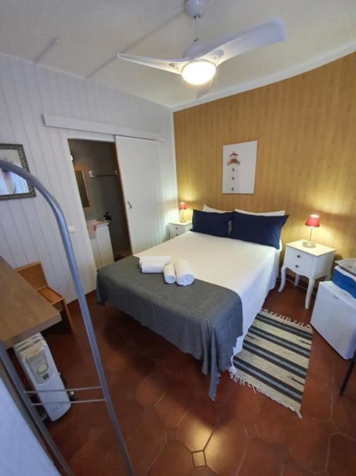 Habitación doble económica en el albergue Ocean View Lagos en Portugal, con cama, ventilador de techo, mesillas de noche con lámparas y
