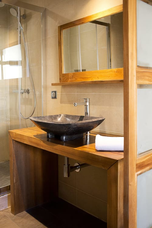 Modern bathroom at AJOUCADOU VIP Lodge in Lourmarin with wooden vanity, black stone vessel sink, and shower