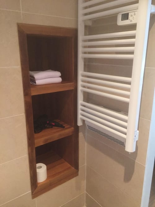 Built-in wooden bathroom shelving with towels and toiletries at AJOUCADOU VIP Lodge in Lourmarin