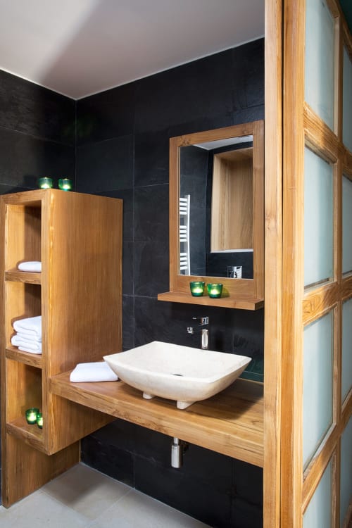 Modern bathroom at AJOUCADOU's The Perch apartment in Lourmarin with wooden vanity, vessel sink, and black tiled walls