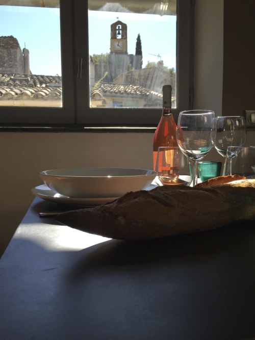 Elegant dining table with rosé wine and glasses overlooking Lourmarin church tower and terracotta roofs at AJOUCADOU The
