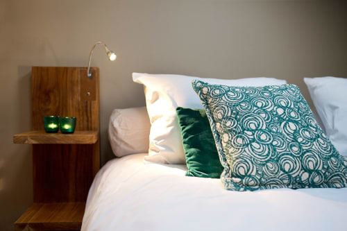Modern bedroom at AJOUCADOU in Lourmarin with wooden nightstand, patterned pillows, and reading lamp