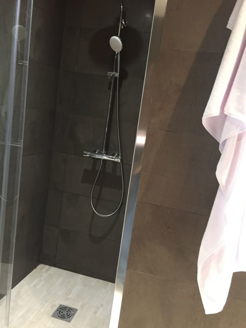 Modern shower with rainfall showerhead and dark tile walls in The Perch apartment at AJOUCADOU, Lourmarin