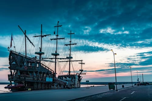 Decorative pirate ship replica at La Maison Du Port harbor in Licata, Italy during twilight