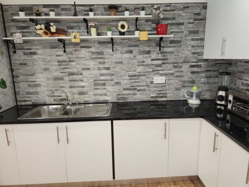 Modern kitchen at Ocean View Lagos hostel with gray tile backsplash, white cabinets, black countertop, and open shelving.