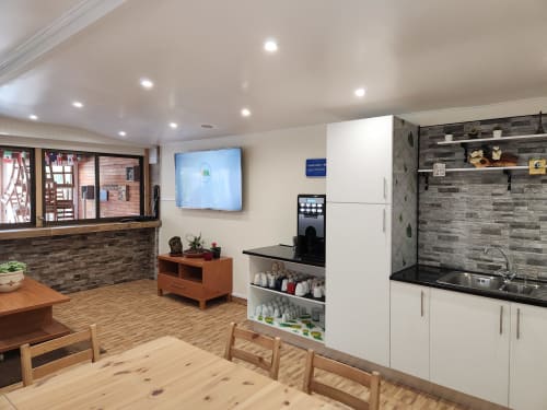 Ocean View Lagos hostel common kitchen with white cabinets, black countertop, wooden dining table, and modern amenities in