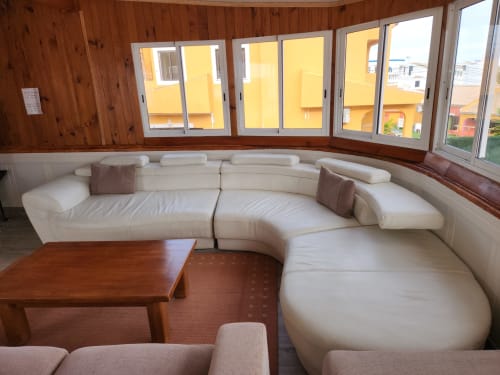 Curved cream leather sectional sofa with wooden table in Ocean View Lagos hostel lounge, Lagos