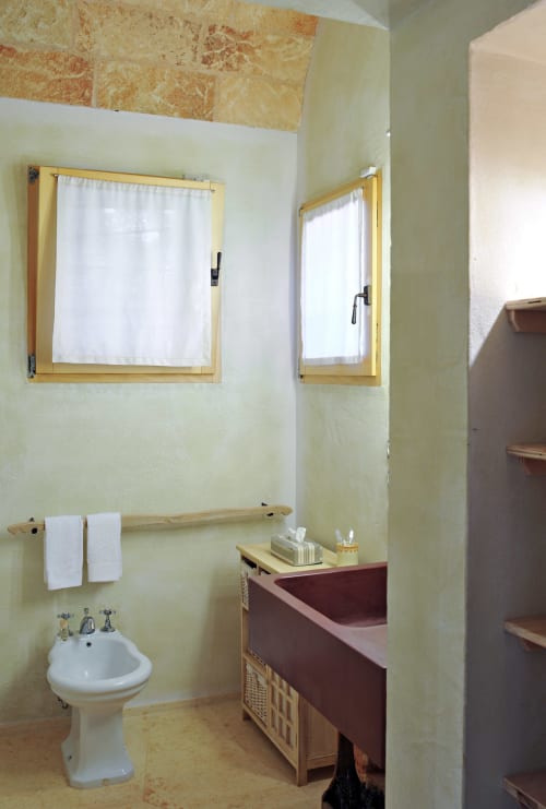Bagno nella camera Barone di Masseria Picca Picca B&B con lavabo rotondo, finestra con cornice in legno e soffitto in cotto.