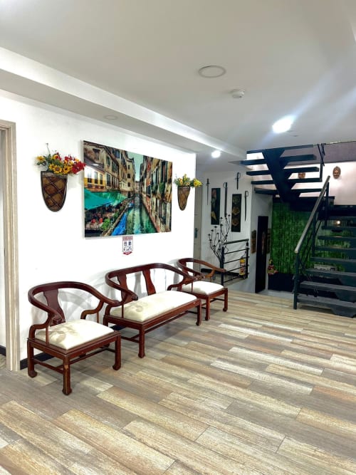 Recepción del Hotel Maderos Cali con sillas de madera, arte de canales venecianos y escalera moderna