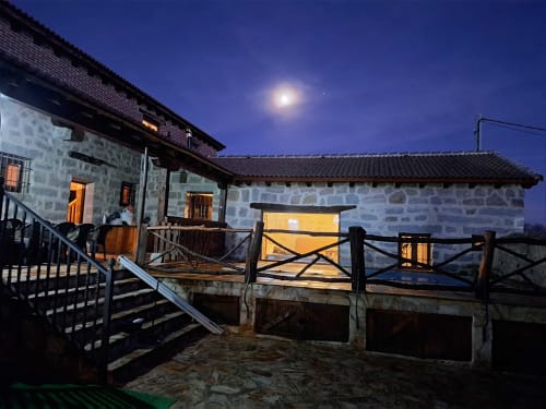 Casa de piedra tradicional en Apartamentos Turísticos Ávila iluminada al atardecer con vistas a las montañas