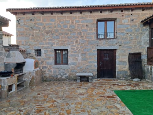 Patio de piedra en Apartamentos Turísticos Ávila con arquitectura tradicional, cocina exterior y vistas a la montaña