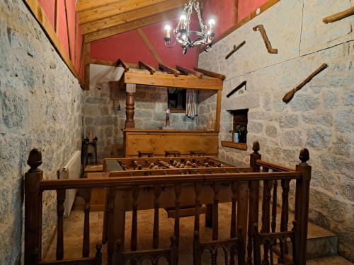 Sala de recreo de casita medieval de piedra con futbolín y vigas de madera en Apartamentos Turísticos Ávila