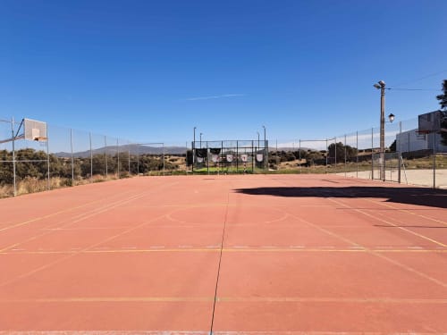 Cancha de tenis al aire libre en Apartamentos Turísticos Ávila con vistas a la montaña y cielo azul despejado