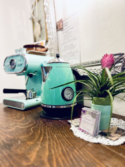 Bouilloire Klarstein turquoise et appareils rétro sur bureau en bois à l'Agritusmo Stecadò, avec fleur rose en pot