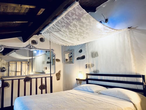 Camera rustica con drappeggi di velo per baldacchino presso l'Agritusmo Stecadò di Dolceacqua, letto in ferro battuto e travi a vista