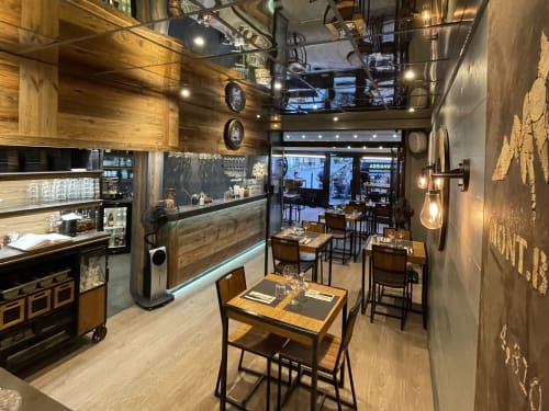 Intérieur moderne du restaurant de La Montagnette B&B à Moutiers avec tables en bois, comptoir de bar et éclairage contemporain