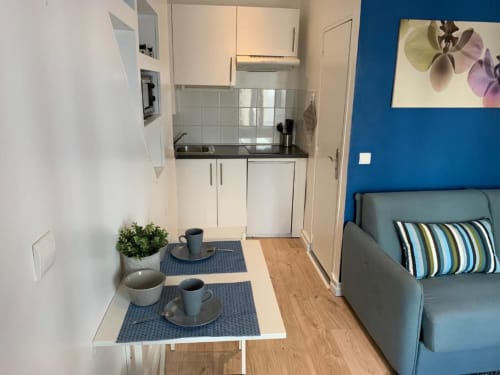 Superior Studio kitchenette at Azur Studios Cannes with dining table, blue accent wall, and sofa bed