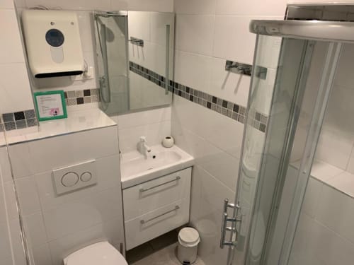 Modern bathroom in Superior Studio at Azur Studios Cannes with white tiles, sink, toilet, shower enclosure and storage