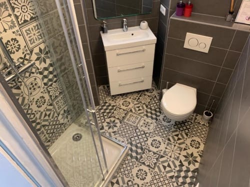 Modern bathroom in Azur Studios Cannes Superior Studio with patterned floor tiles, white vanity, toilet, and shower enclosure